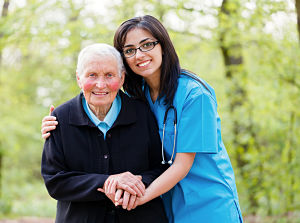 Smiling Female Nurse hugging an elderly male patient from the side and holding the man&apos;s  man.